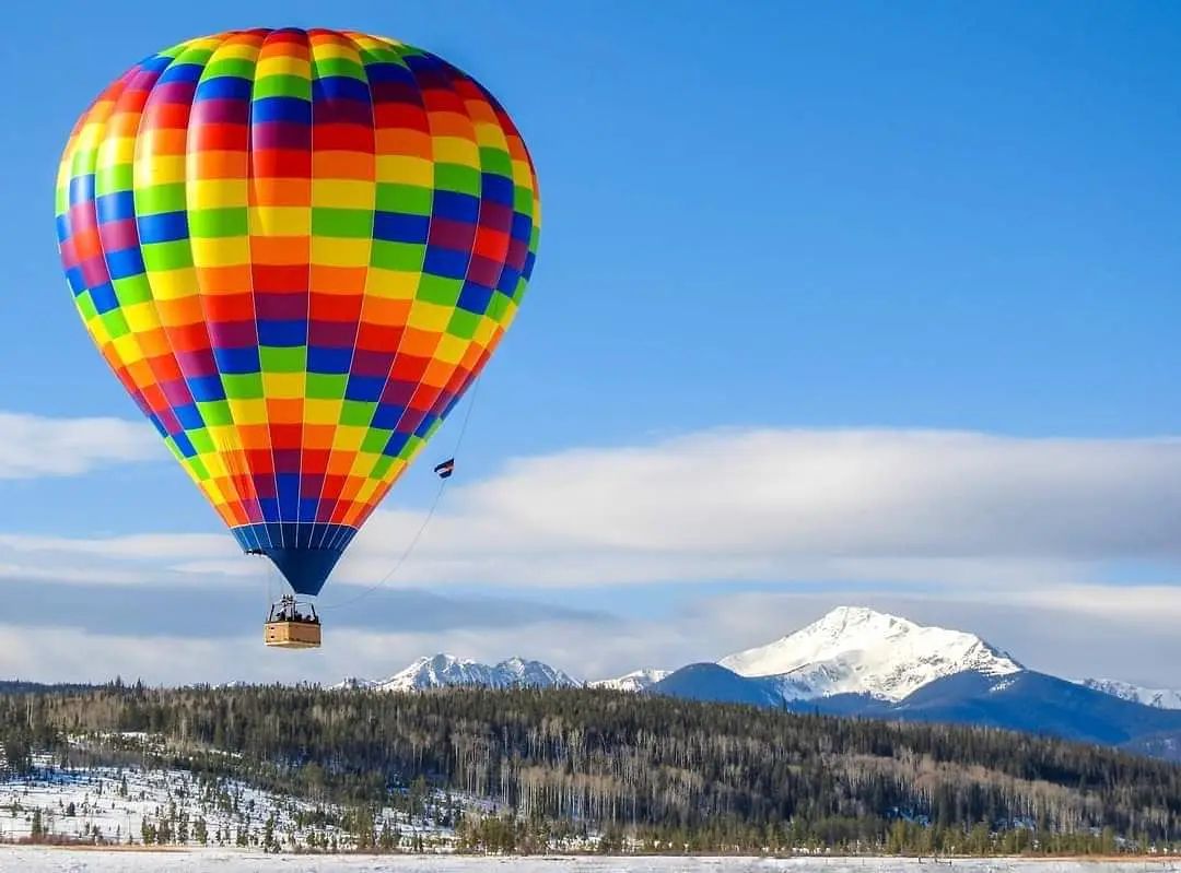 Colorful balloon soaring over snowy mountain landscape